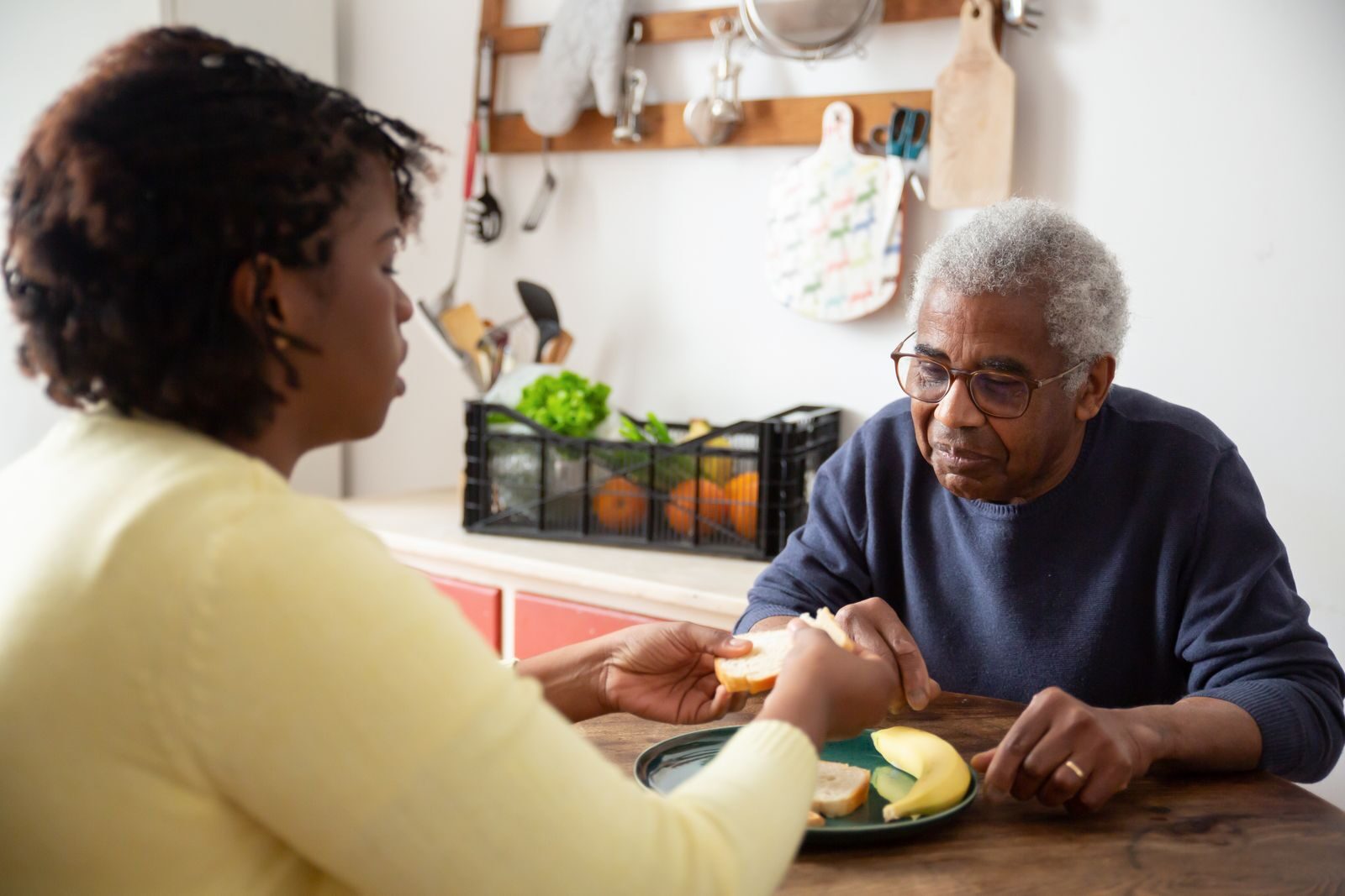 A caregiver and her client sharing lunch at the kitchen table